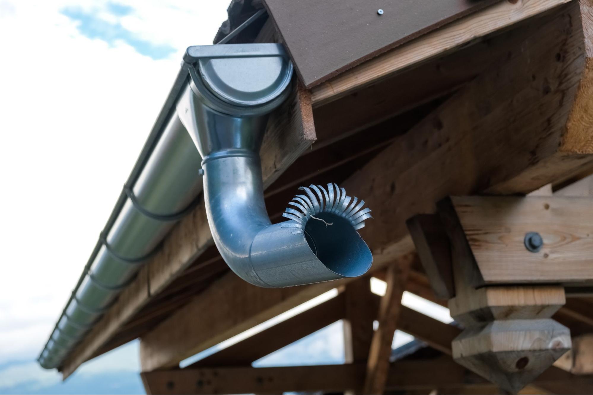 A metal drain pipe on the mountain cabin roof wing.