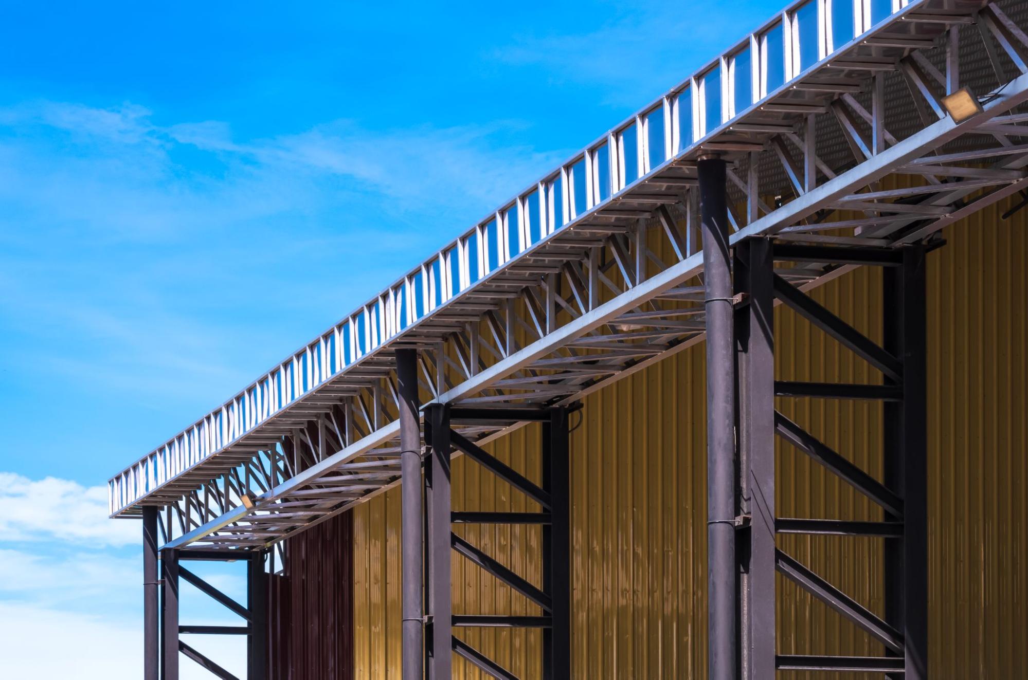 An aluminum roof gutter with steel rainwater pipes is on an outdoor multi-purpose building.