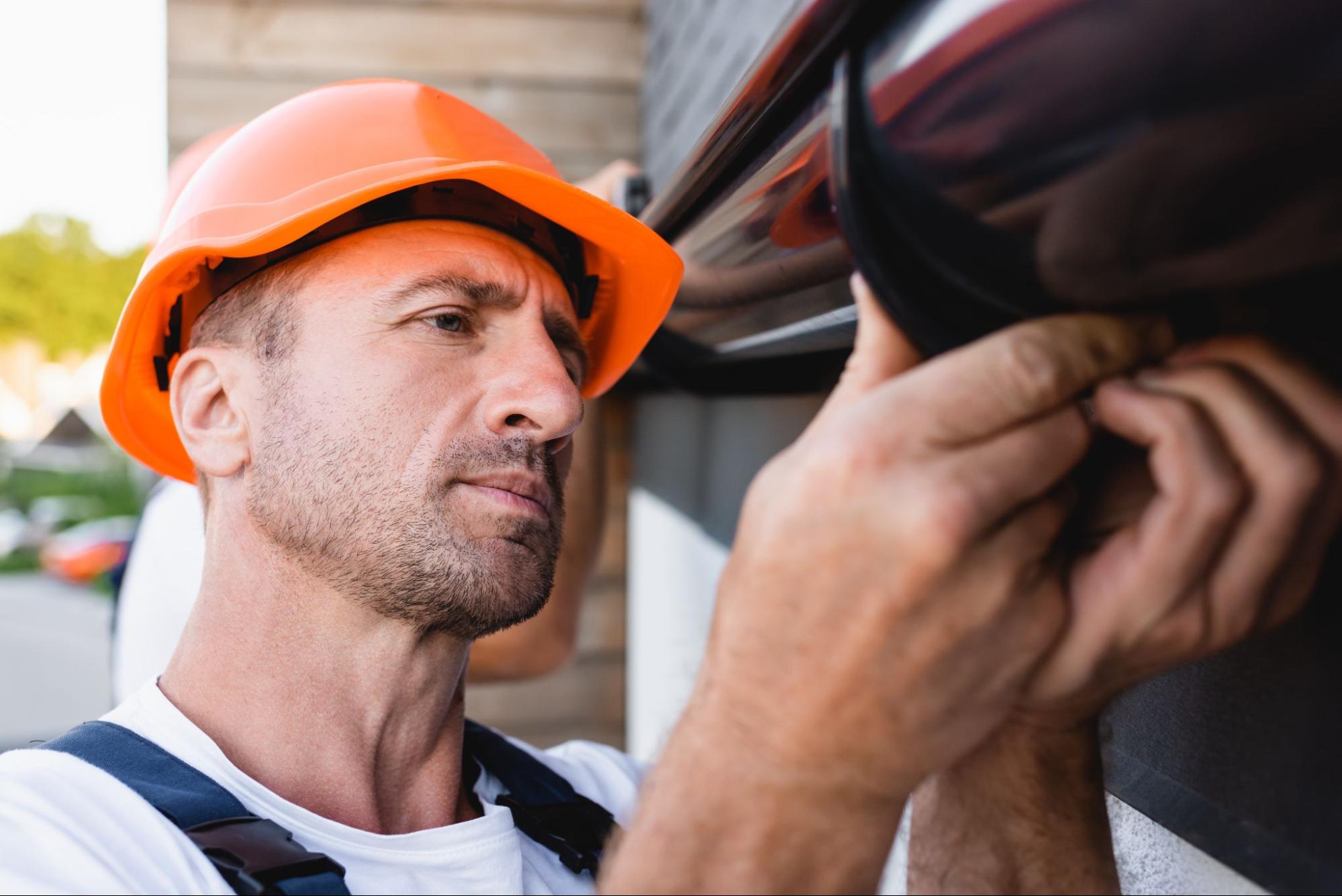 A builder checks the rain gutter attached to the building facade