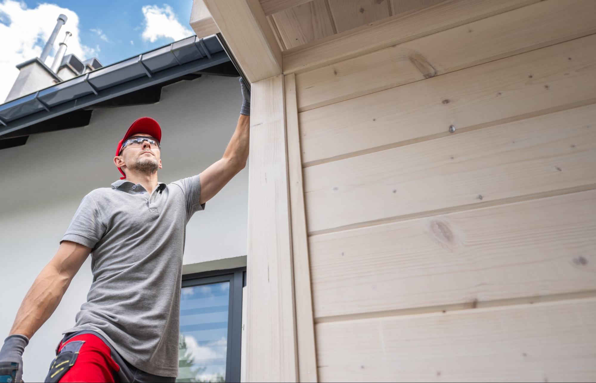 Worker performing gutter services and maintenance on the exterior of a house.