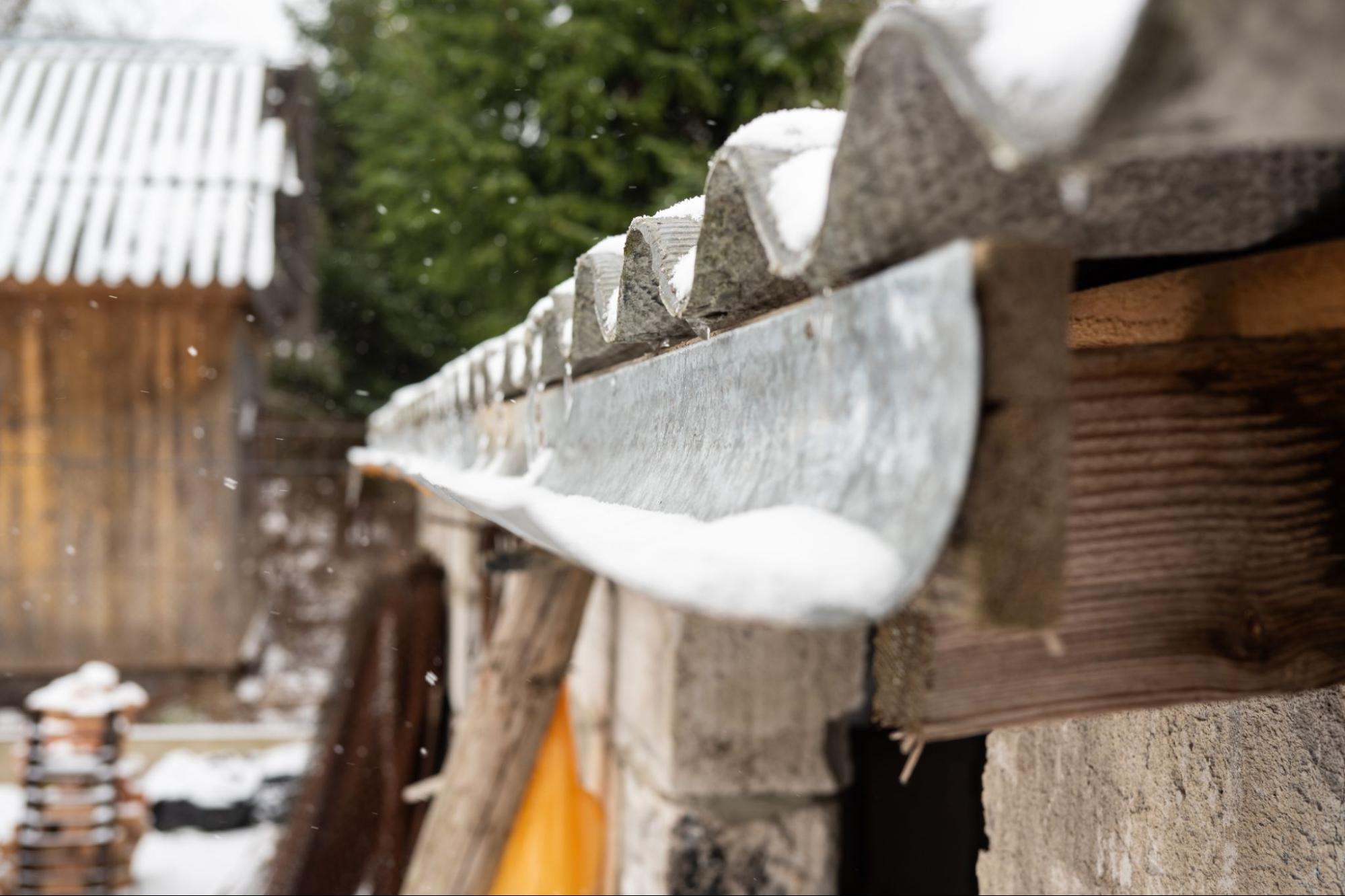 A snow-covered gutter surrounded by trees in a quiet rural winter landscape