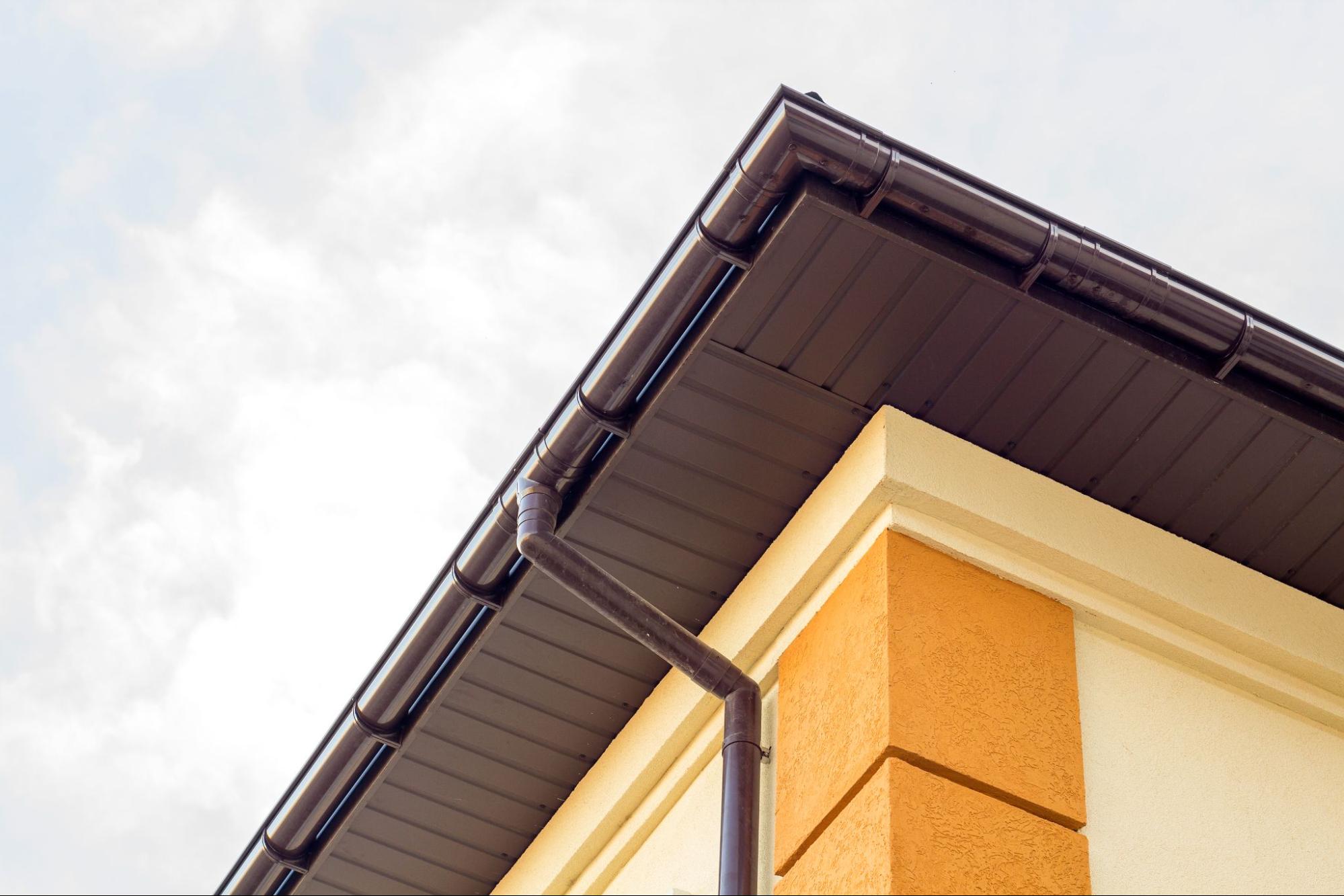 Upward view of a cottage house corner showing seamless gutters