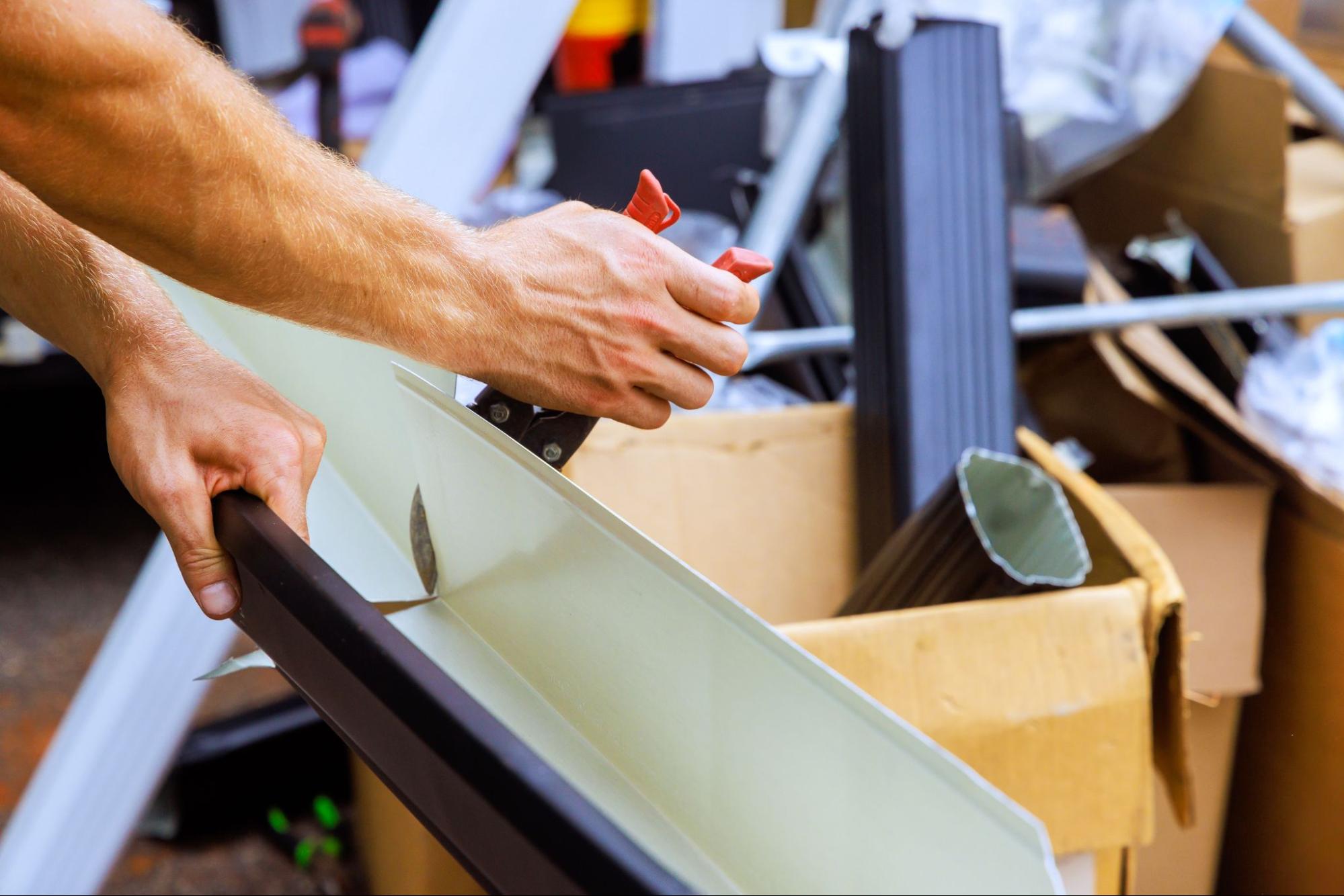 Cropped view of a worker cutting a rain gutter section for installation