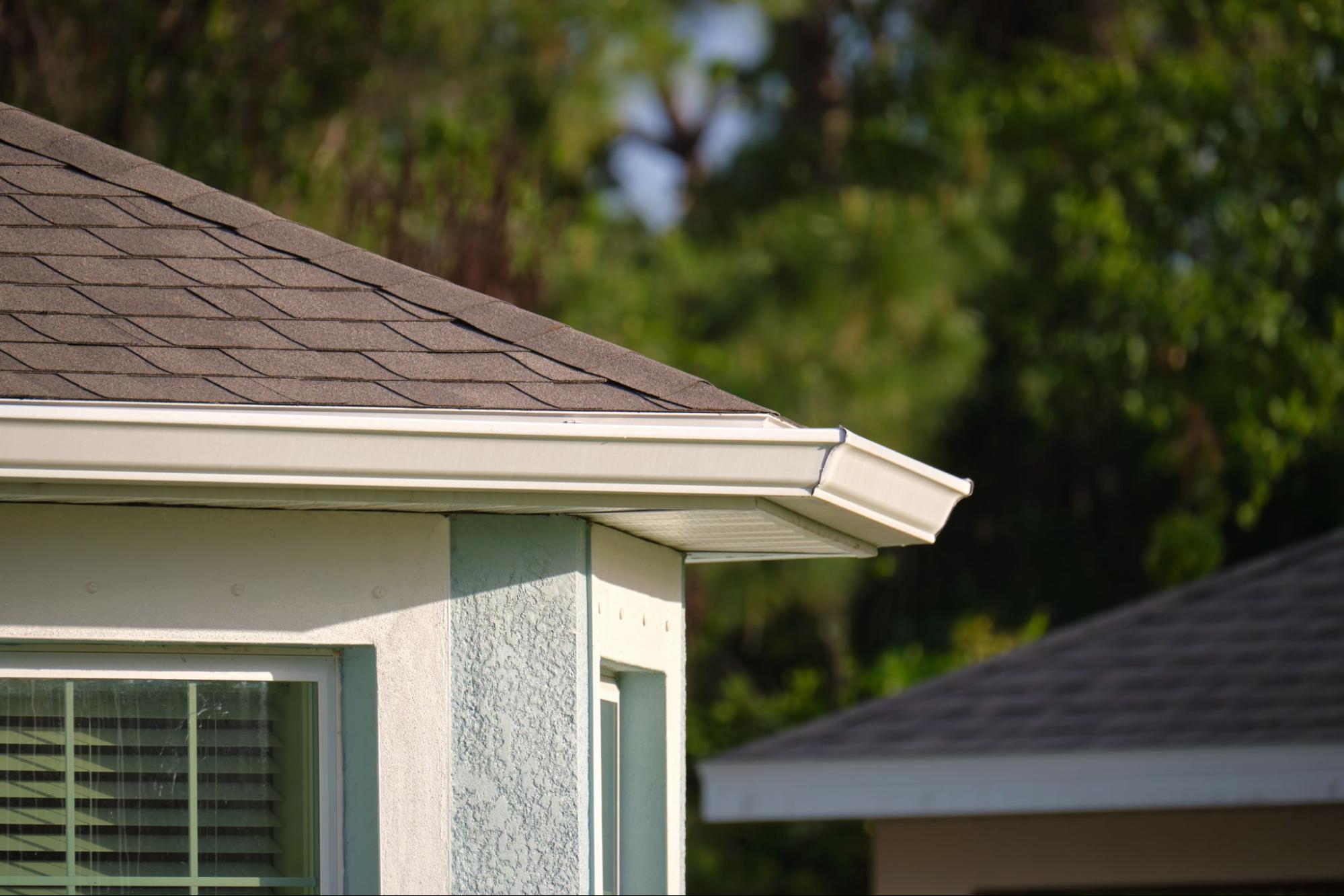 Partial view of a home roof with a gutter system that reduces clogs and improves drainage performance