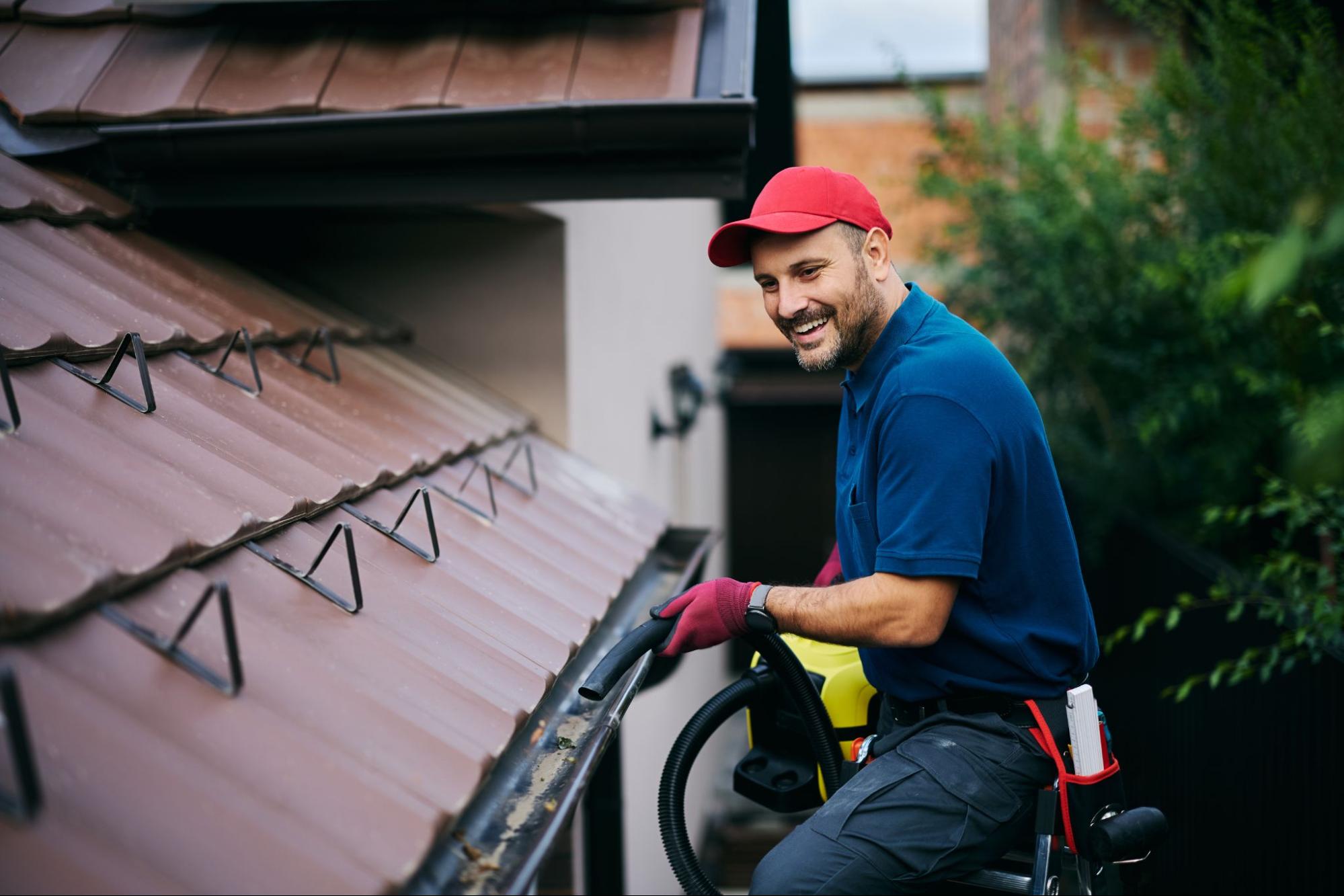 Worker maintaining rain gutters on a suburban residential property