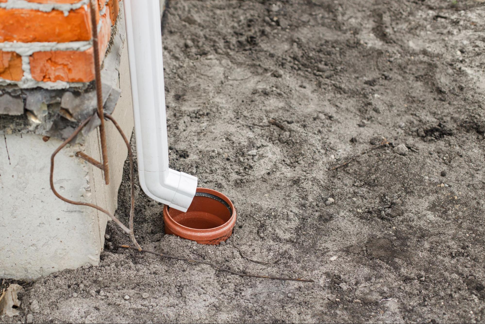 Under-construction gutter drain pipe system fixed to red brick building wall