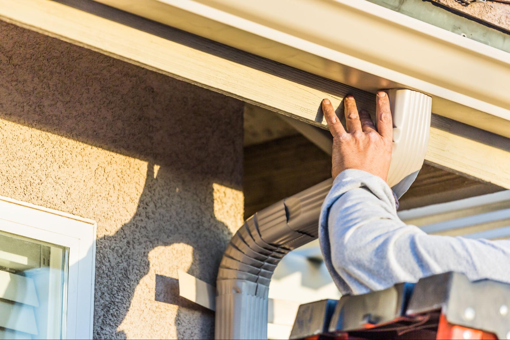 Close-up of technician’s hand securing gutter system