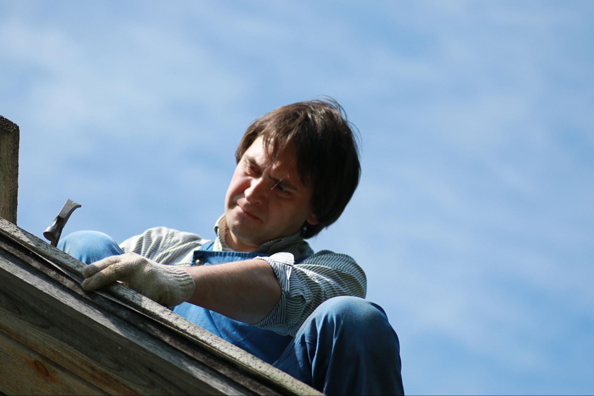 A man repairing rain gutters on a residential roof to fix drainage issues
