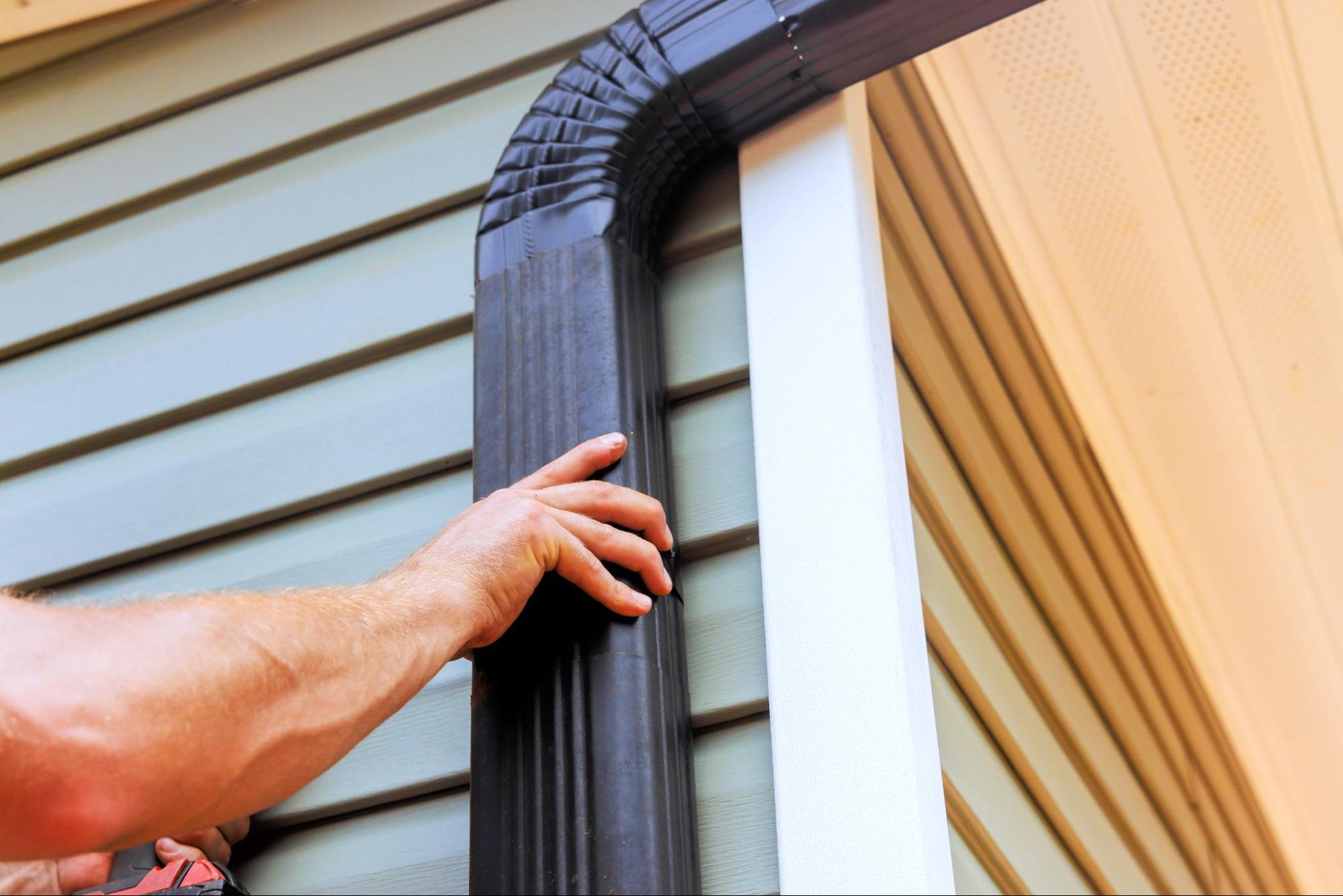 Contractor securing gutter system to exterior wall