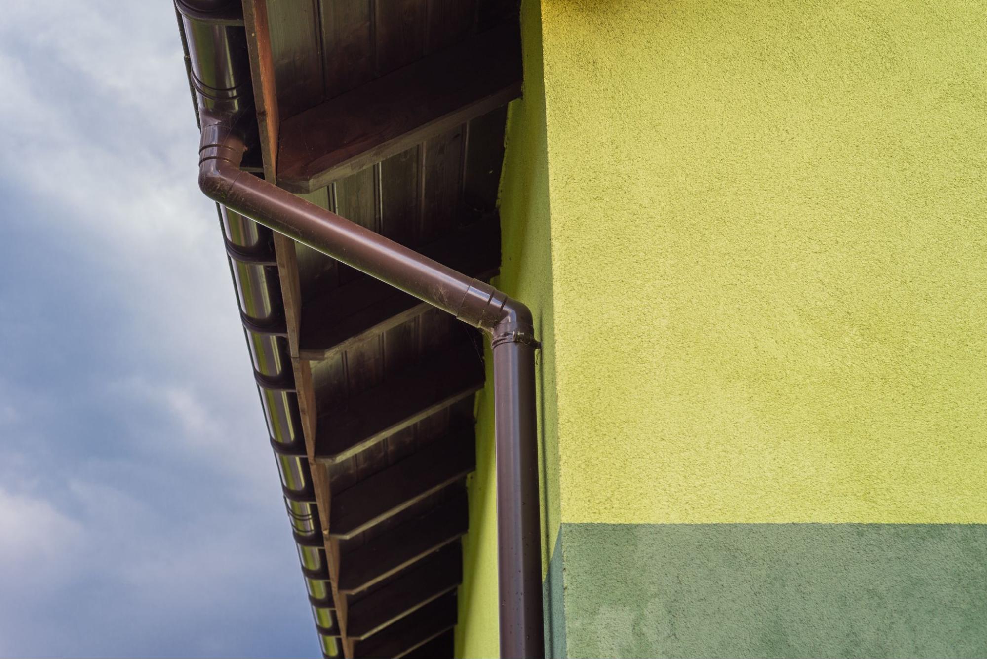 Light green house exterior with visible roof soffit and professionally installed rain gutter system along the roofline.