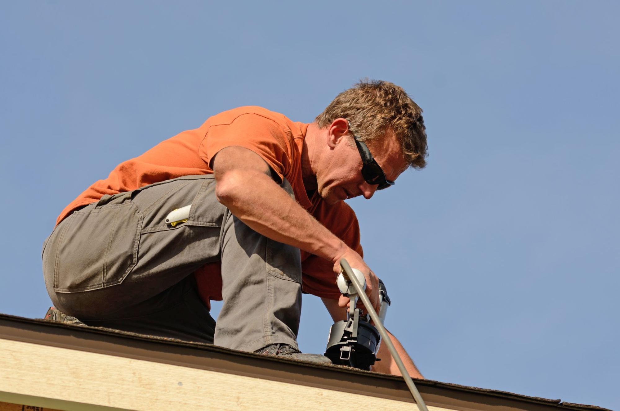 Roofing professional preparing an apartment building for seamless gutter installation