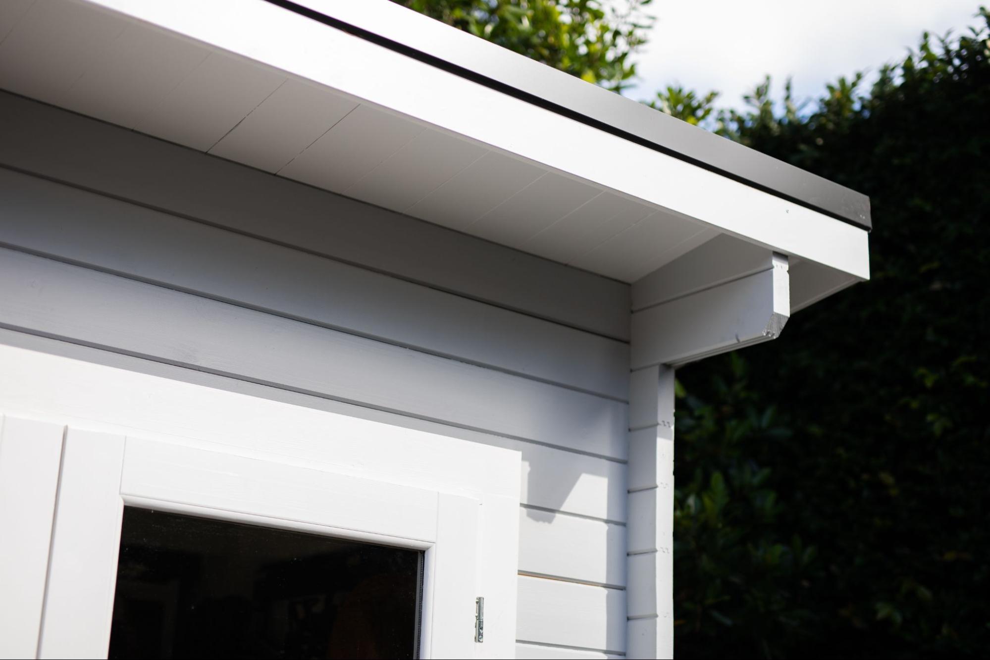 Corner detail of a white wooden home showing fascia and soffit along the roofline