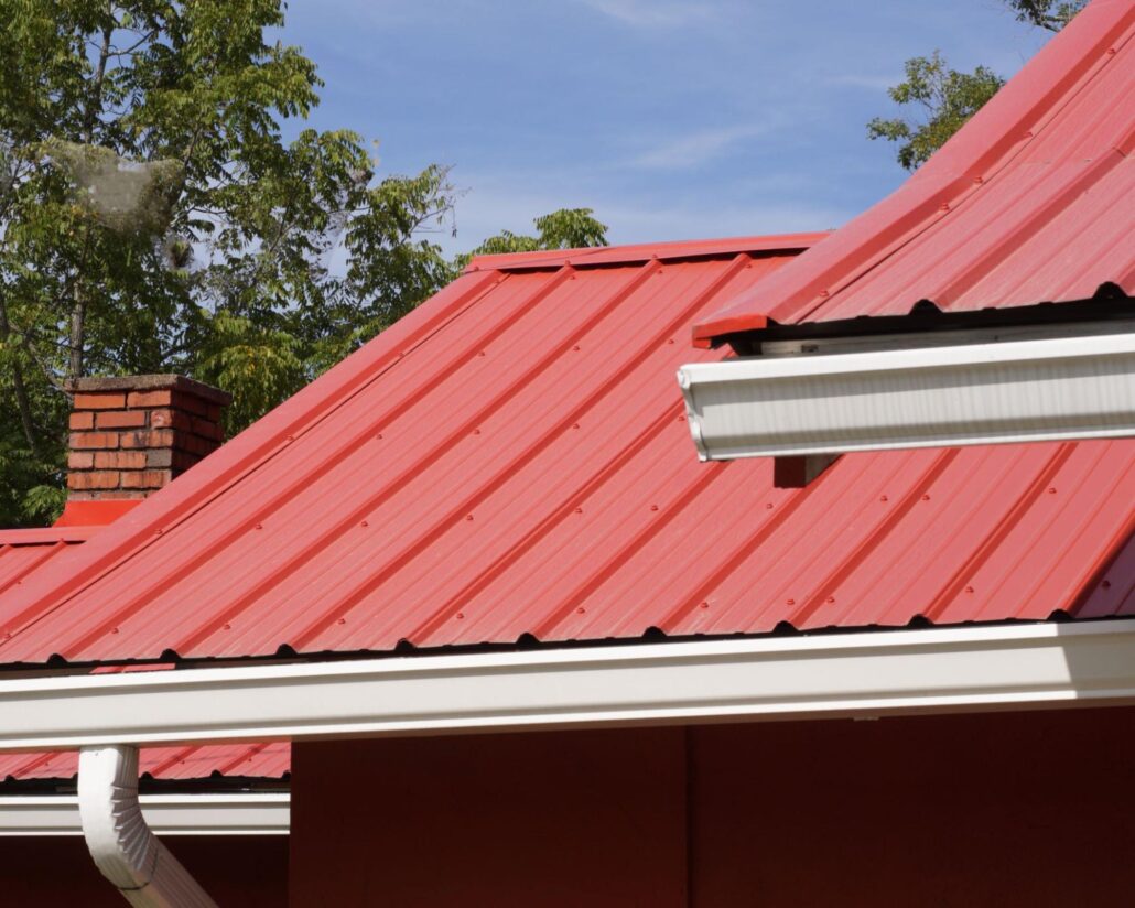 Close-up of a red metal roof featuring a seamless gutter system for efficient rainwater drainage