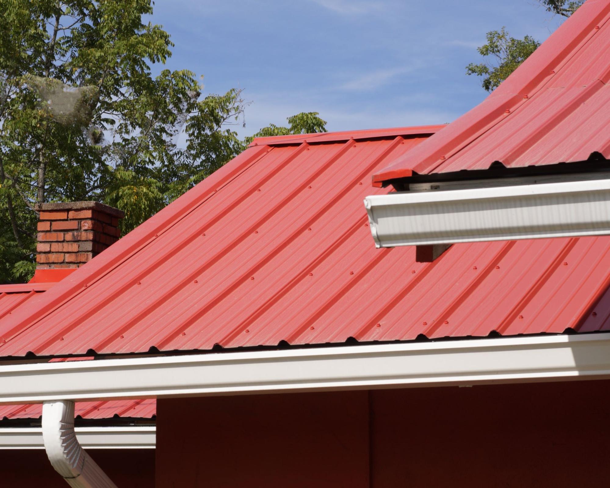 Close-up of a red metal roof featuring a seamless gutter system for efficient rainwater drainage