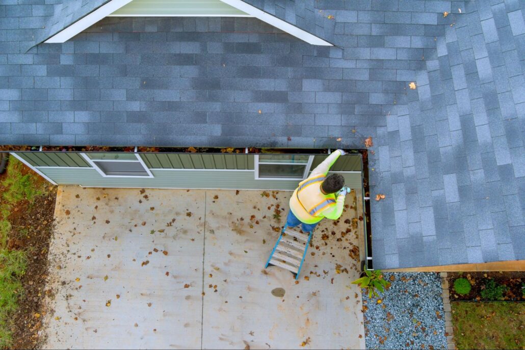 Overhead view of a worker cleaning gutters on the home exterior roofline
