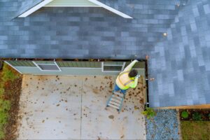 Overhead view of a worker cleaning gutters on the home exterior roofline