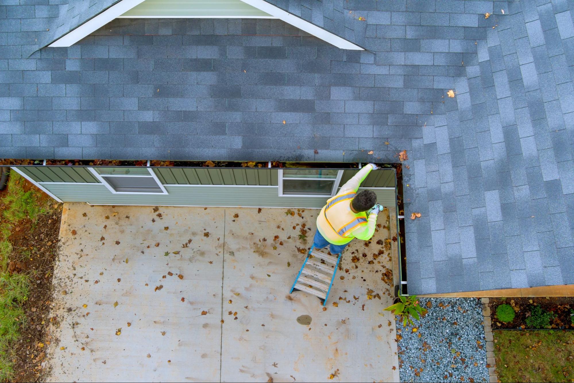 Overhead view of a worker cleaning gutters on the home exterior roofline