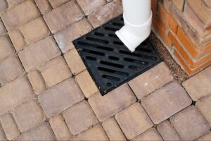 Gutter drainage system directing rainwater across a brick-paved patio surface