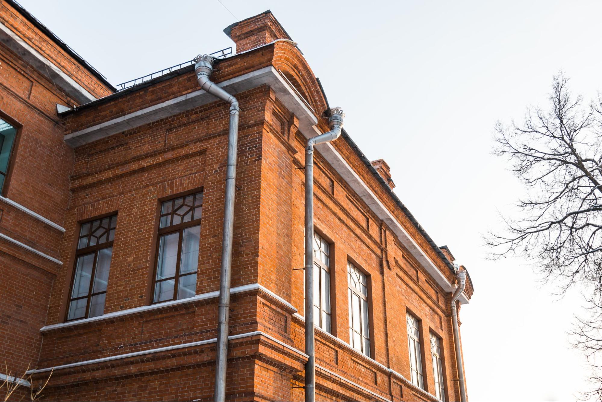 Tall brick residential complex with metal downspouts channeling rainwater safely away from the building exterior