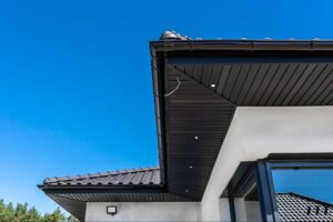Modern house exterior with dark-trimmed roof and seamless gutter system