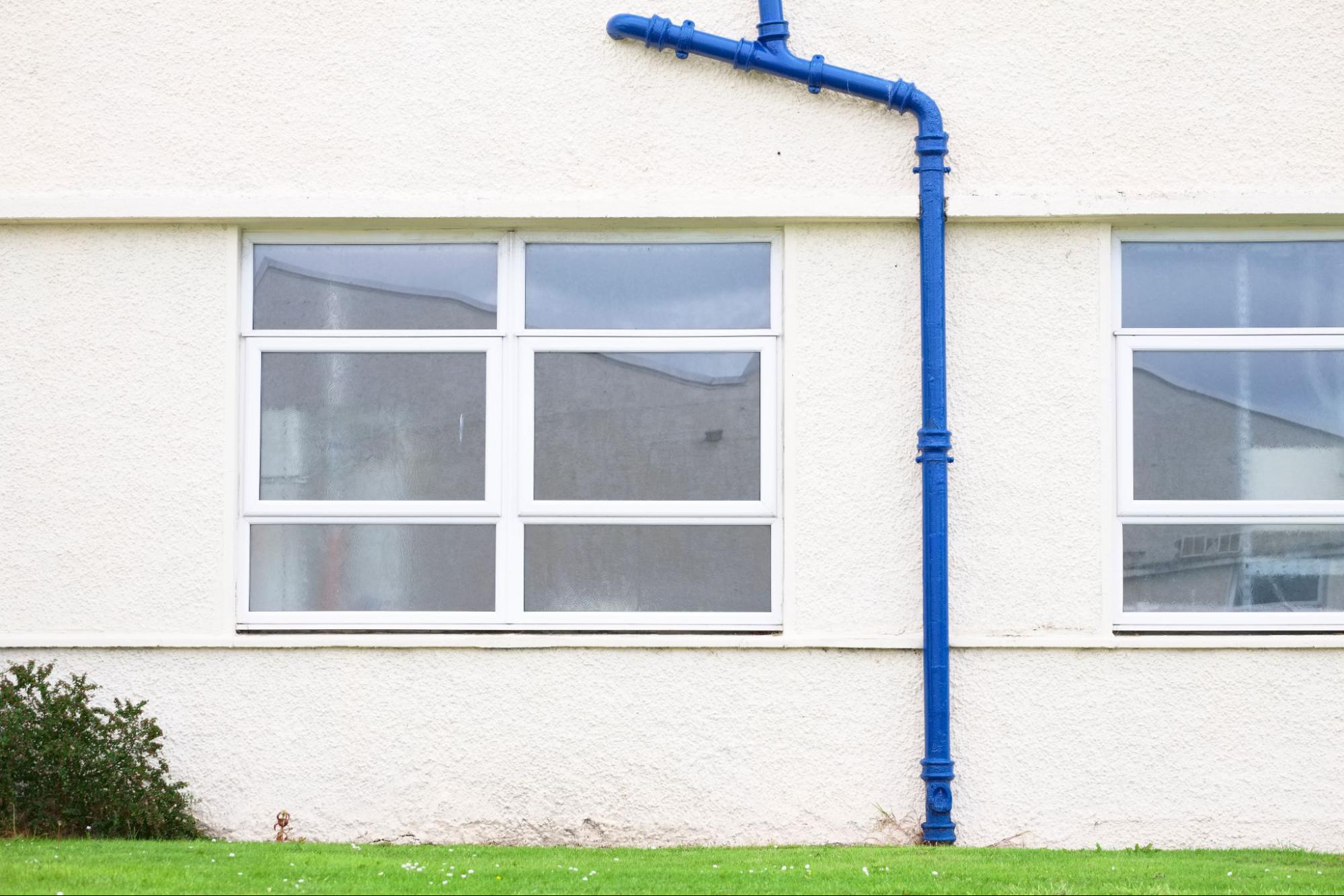 Cast iron downspout drainage pipe installed outside a building to direct rainwater away from the property